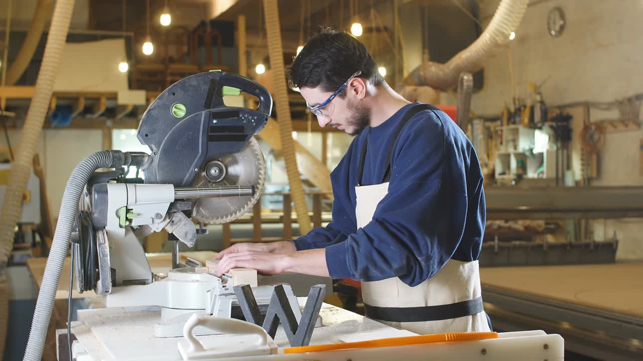 Bell'uomo falegname caucasico che lavora usando una macchina per il taglio del legno.