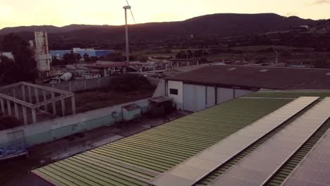 Green-energy,-aerial-shot-of-warehouse-with-solar-panel-and-wind-turbine