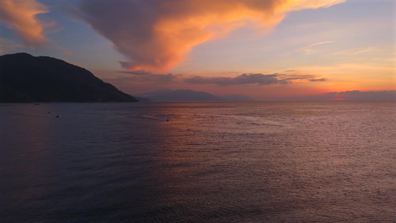 Wide drone shot of tropical ocean and colorful sunset horizon