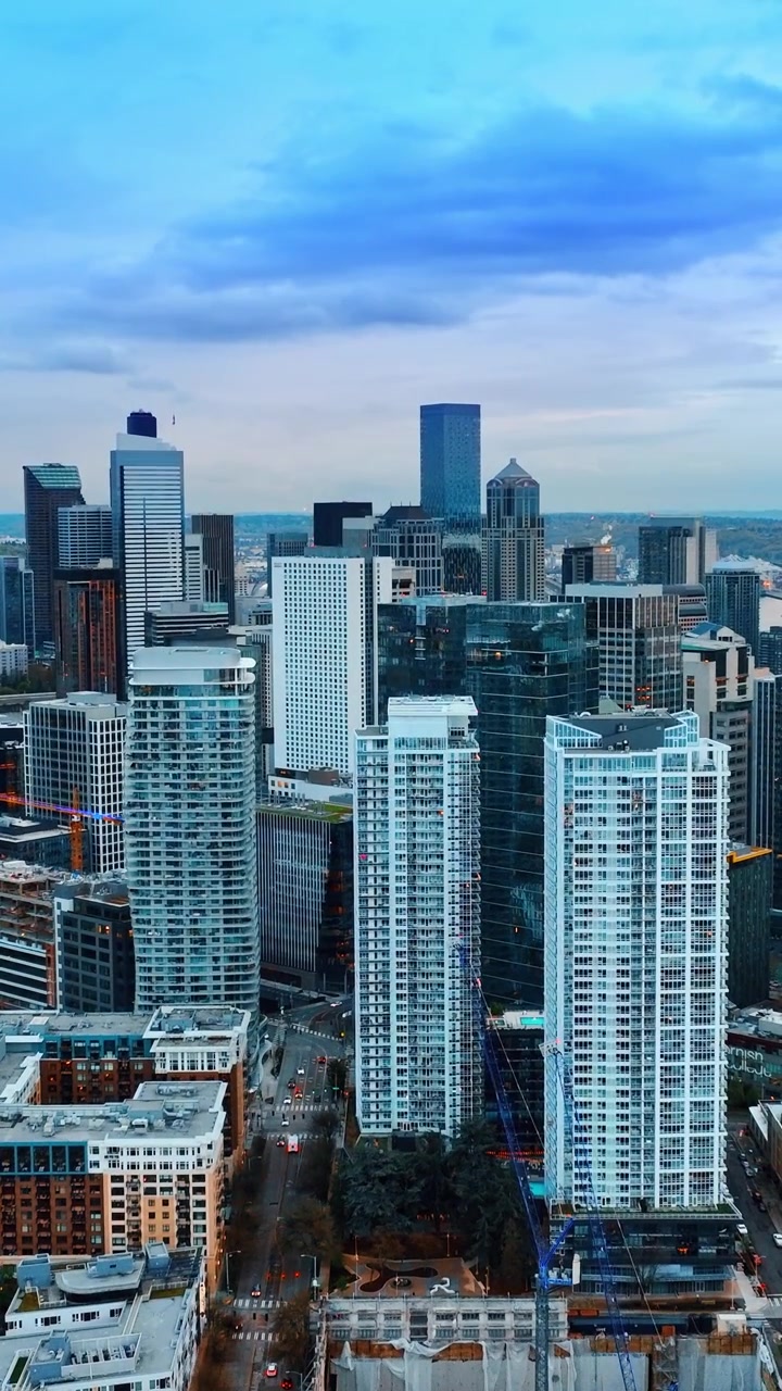 Un gruppo di grattacieli simili nel centro di Seattle, Washington, Stati Uniti. Drone che si alza sopra il paesaggio urbano la sera. Video verticale