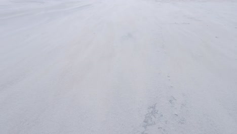 View-of-white-sandy-beach-during-wild-and-windy-sandstorm-with-streams-of-sand-flying-and-moving-across-surface-on-West-Beach-in-Berneray,-Outer-Hebrides-of-Western-Scotland-UK