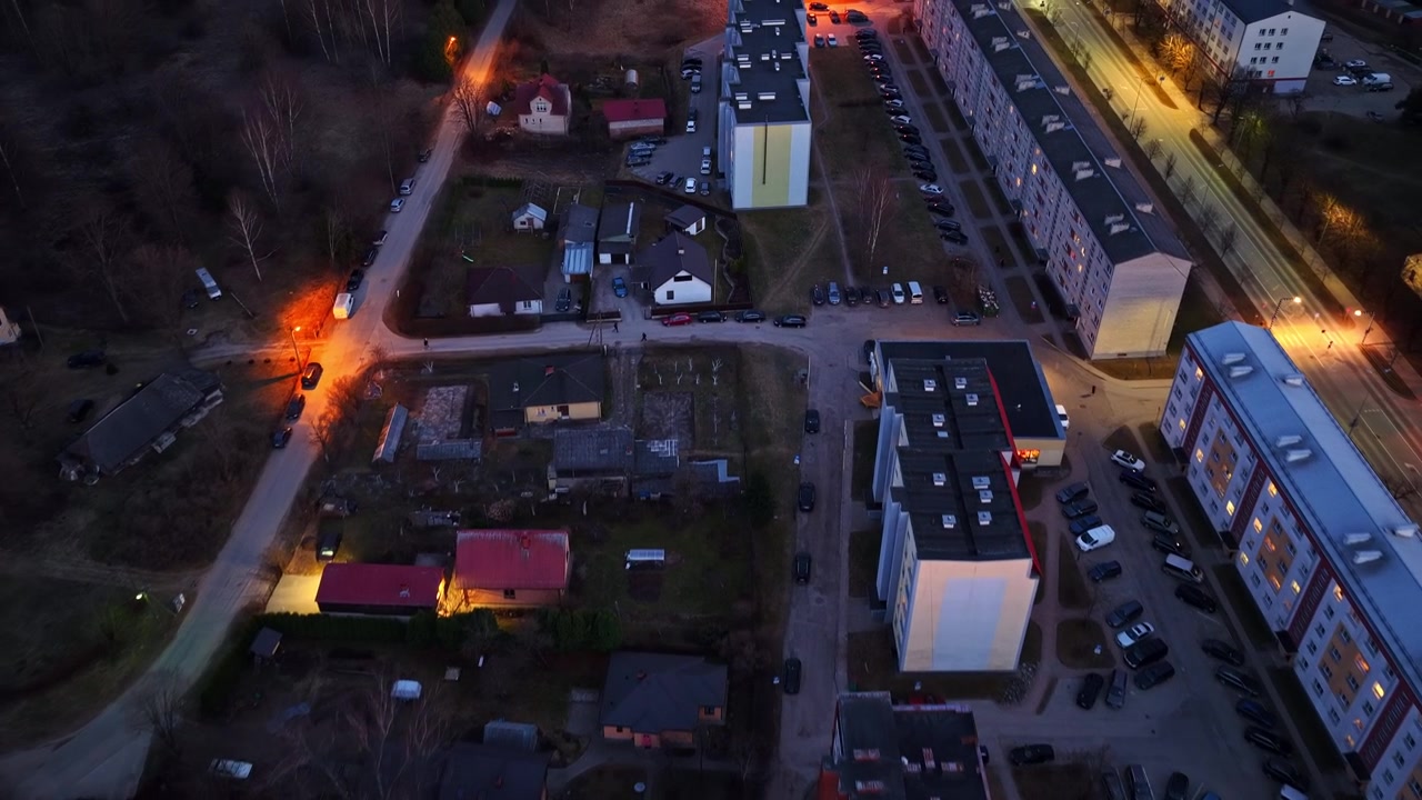 Dron latający nad cichą dzielnicą mieszkalną z budynkami mieszkalnymi i ulicami o zmierzchu