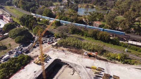 vista circular de drones de nuevos sitios de construcción con una gran grúa torre en buenos aires un tren que pasa en el fondo