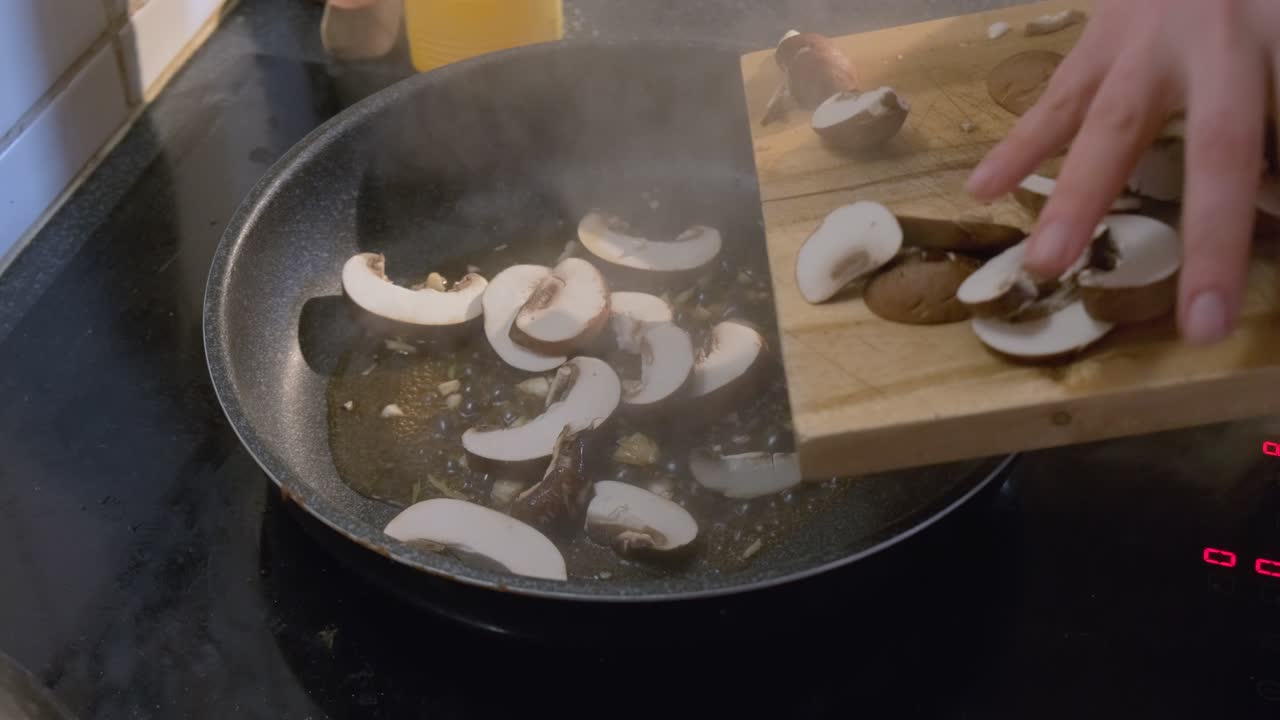 Close up of fresh sliced mushrooms being tossed in a cooking pan for a delicious healthy recipe