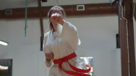 medium shot of focused teenager practicing karate in gym