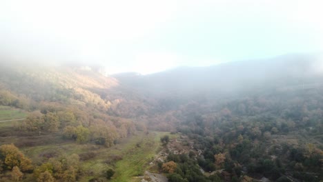 Osona's-autumn-landscape-at-sunrise,-fog-gently-covering-the-hills,-aerial-view