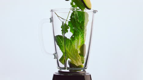 closeup blender green vegetable falling in bowl super slow motion. organic food