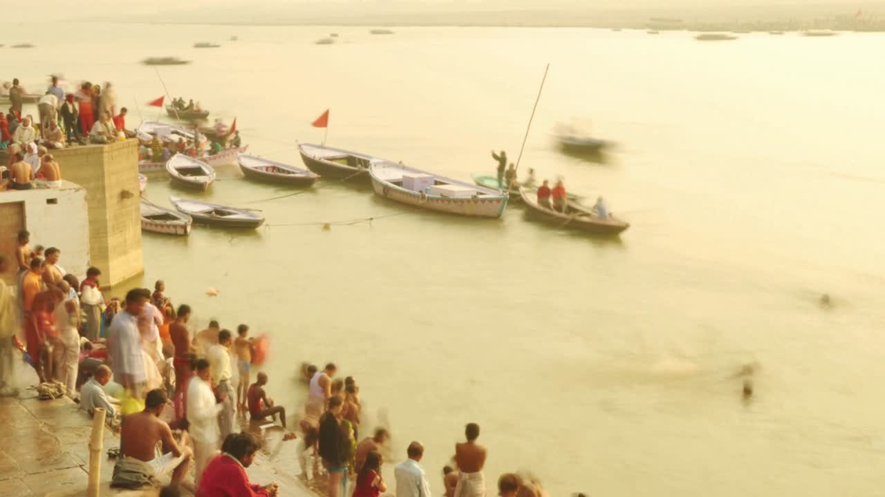 el lapso de tiempo de los peregrinos indios remando en un barco al amanecer. río ganges en varanasi, india.