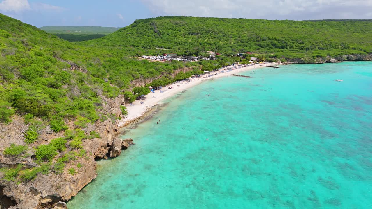 Il drone si spinge oltre le falesie rocciose verso Playa Porto Mari in una splendida giornata di sole.