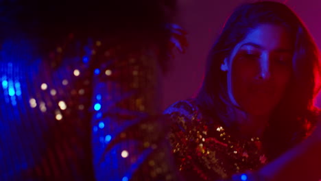 Close-Up-Of-Two-Women-In-Nightclub-Bar-Or-Disco-Dancing-With-Sparkling-Lights