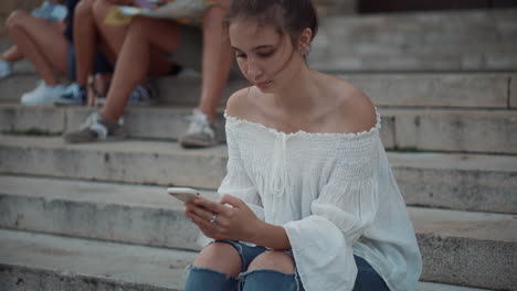 adolescente usando un teléfono inteligente en las escaleras con amigos