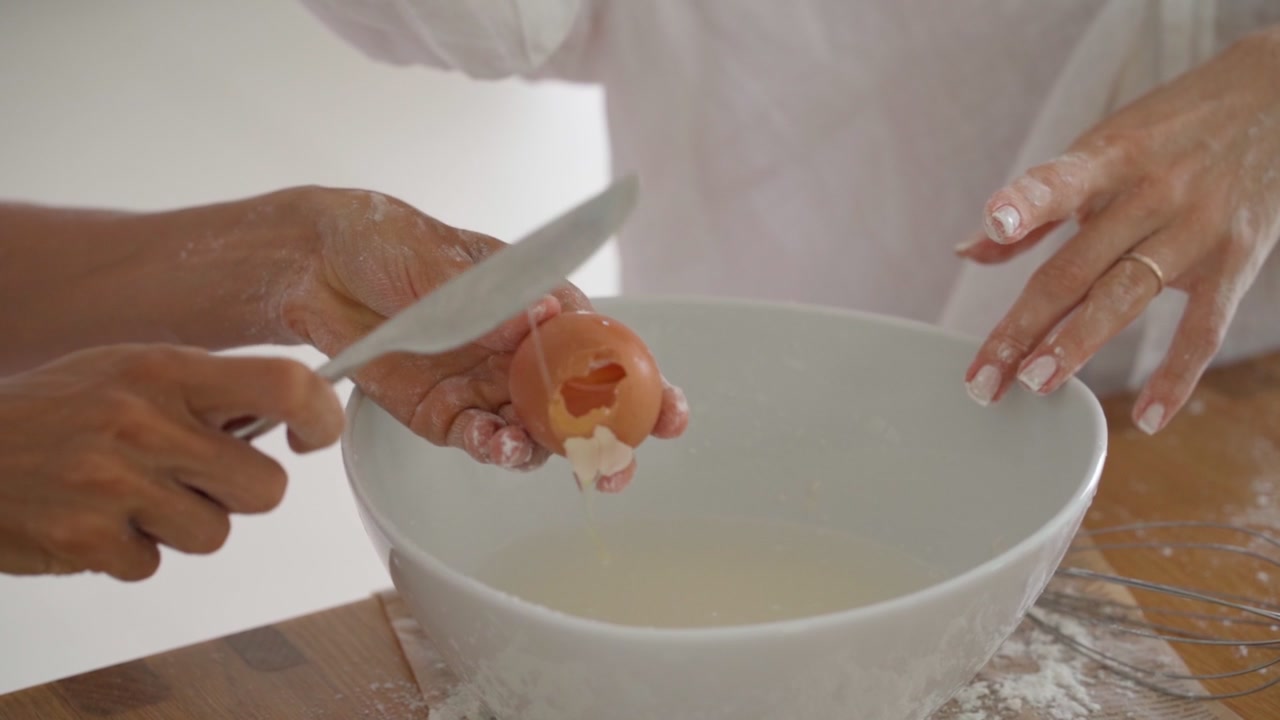 Person Cracking Egg into Bowl While Baking