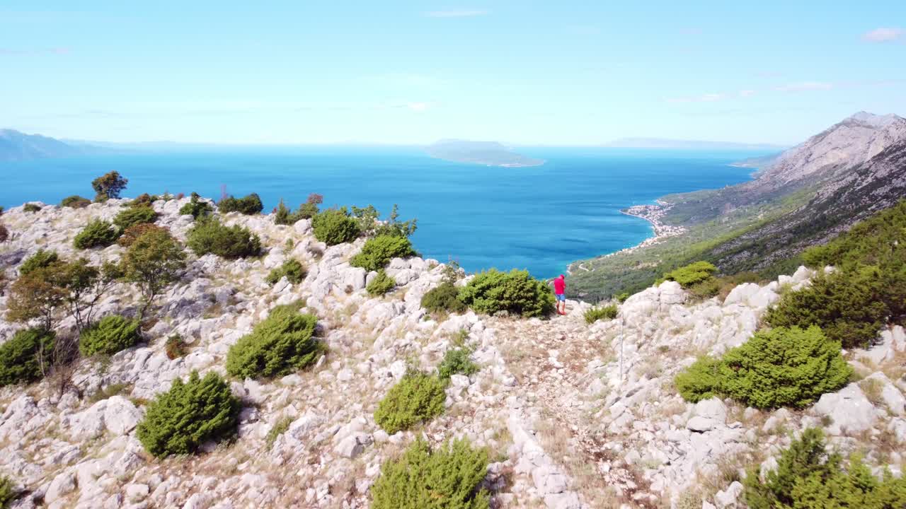 Aerial dolly to hikers traversing rocky paths on Mount St. Ilija, Croatia, panoramic views and rugged terrain overlooking stunning ocean waters