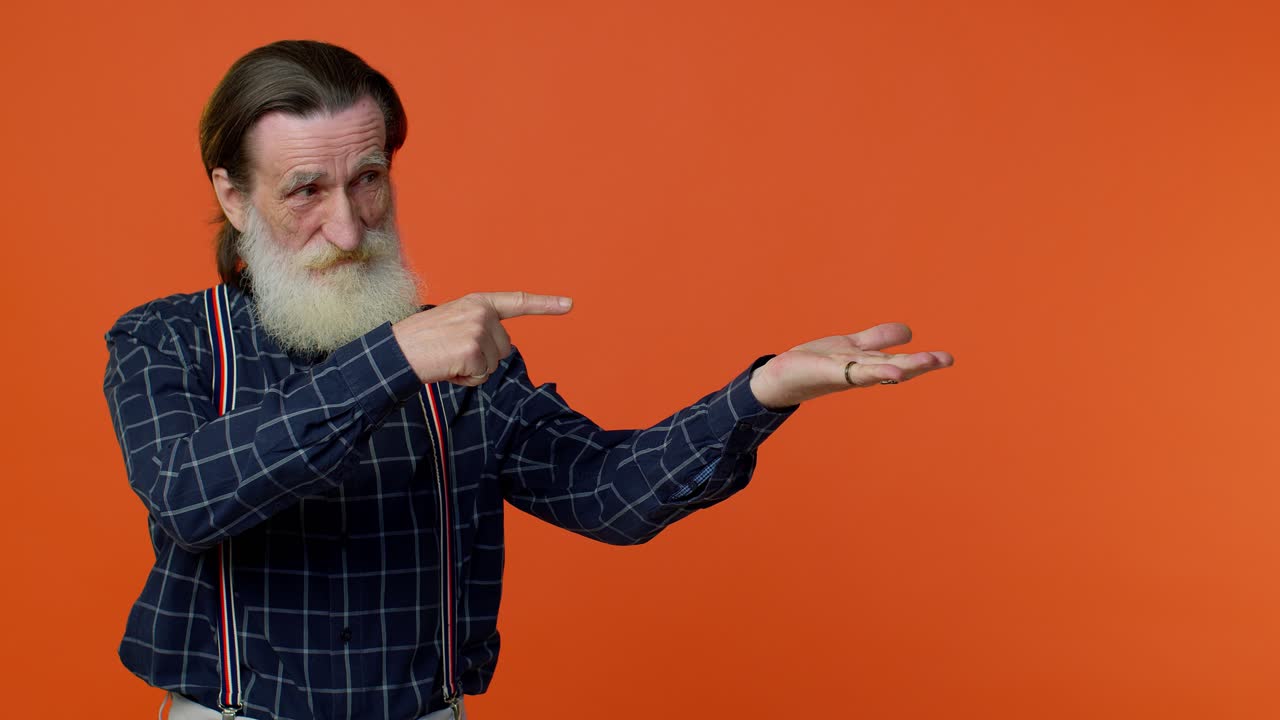 abuelo maduro mostrando los pulgares hacia arriba y señalando un lugar vacío, área de publicidad para texto comercial