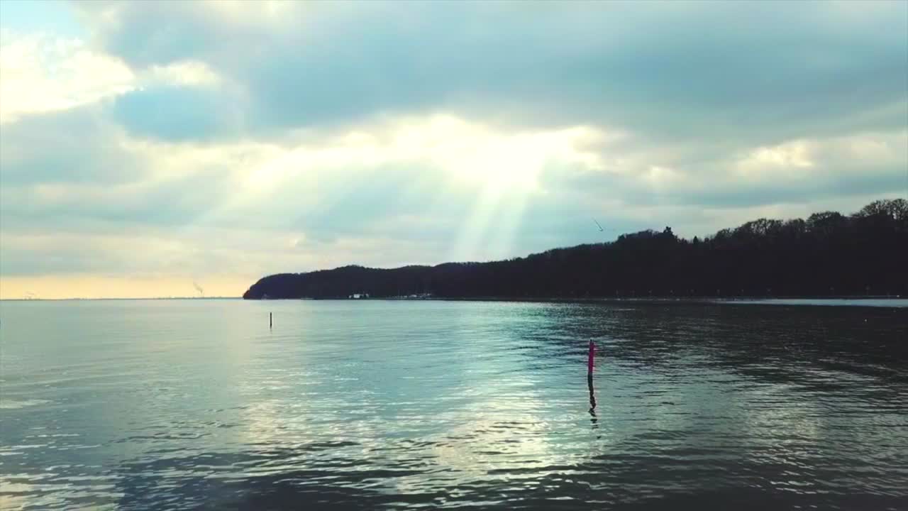 해변 위의 구름을 통과하는 태양 광선 - 드론