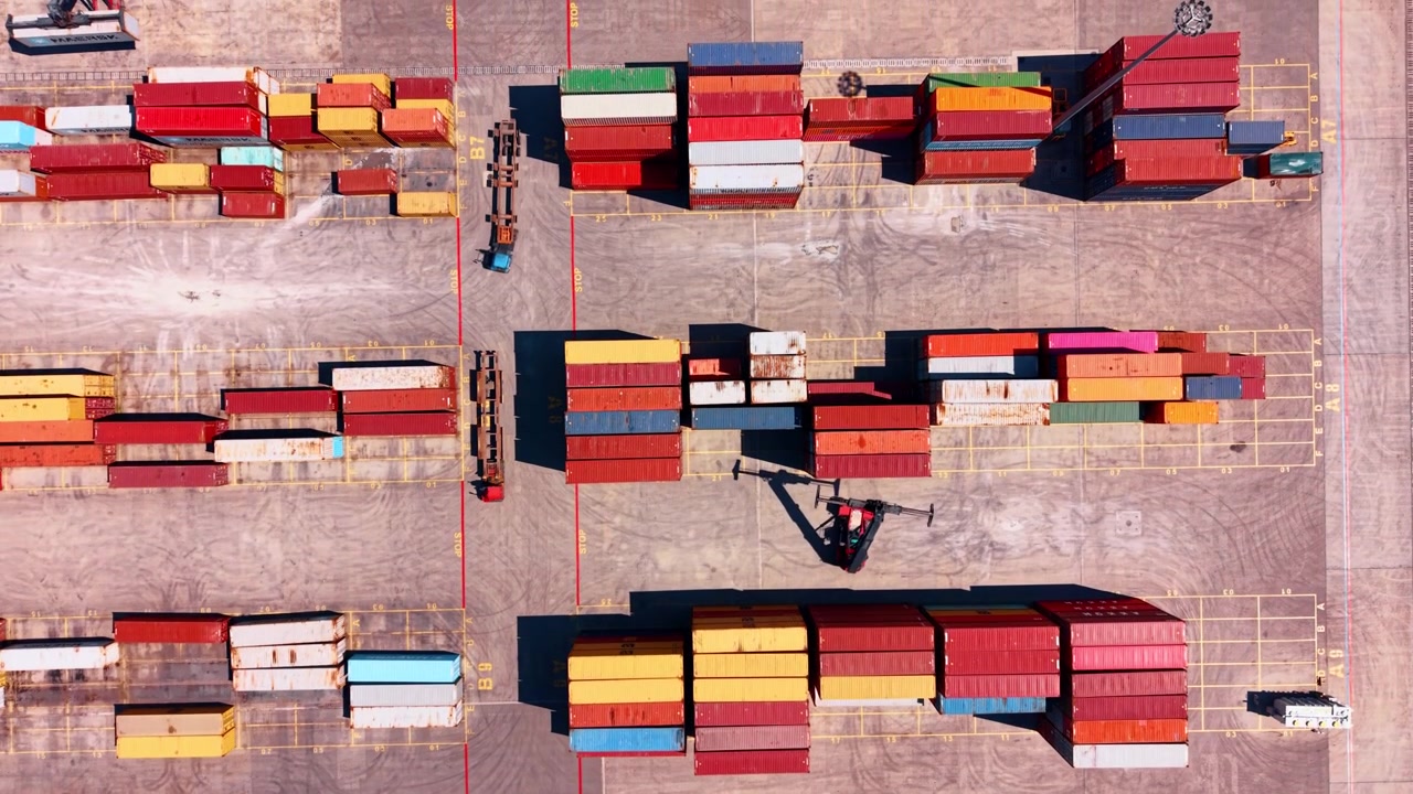 Burgas, Bulgaria, 1 May 2026: Top view of container stacks in cargo terminal. Vertical drone shot of stacked containers, terminal lanes, yard markings, forklifts and long shadows.