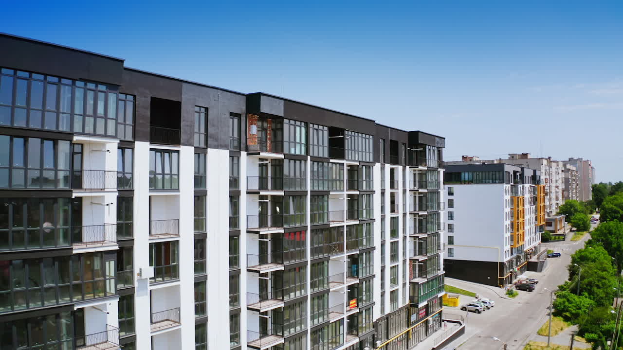 New highrise building in the city street. Modern design of newly built apartment building with large glassed balconies on urban background. View from the air.