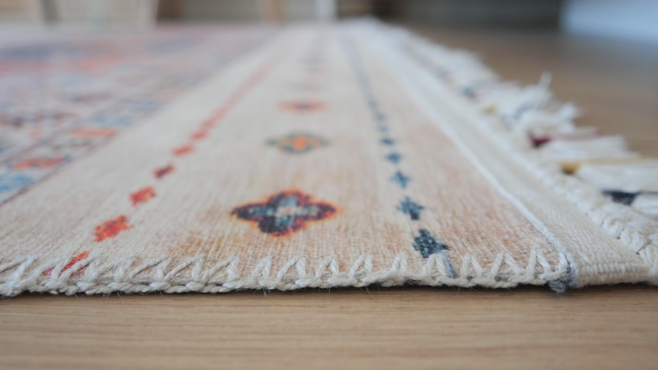 Close-up of a Colorful Patterned Rug with Tassels on a Wooden Floor