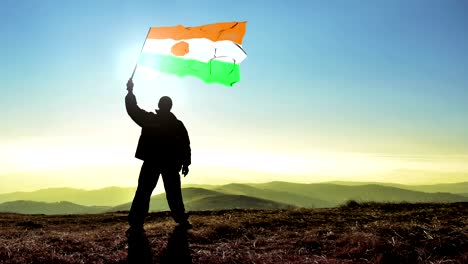 hombre ganador de silueta exitosa agitando la bandera de níger en la cima de la montaña, fondo de bucle de cinemagraph