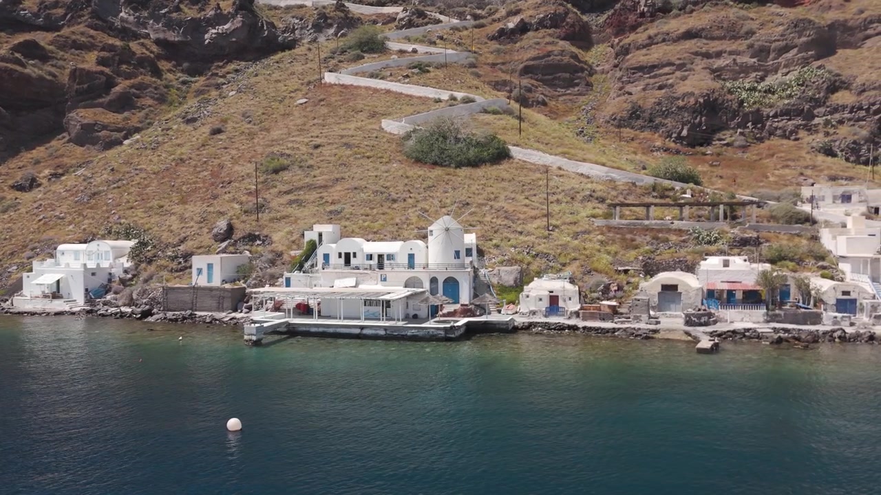 Vista panoramica del villaggio tradizionale e della costa dell'isola di Thirasia, parte dell'arcipelago di Santorini. Ripresa aerea, con movimento in avanti