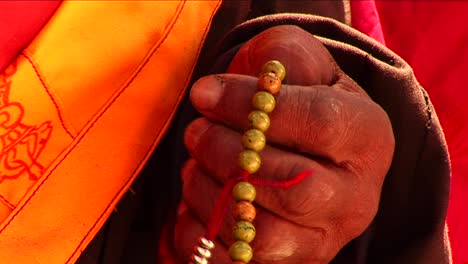 closeup of lama using prayer beads