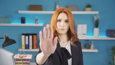 mujer de negocios mirando a la cámara haciendo una señal de parada con la mano.