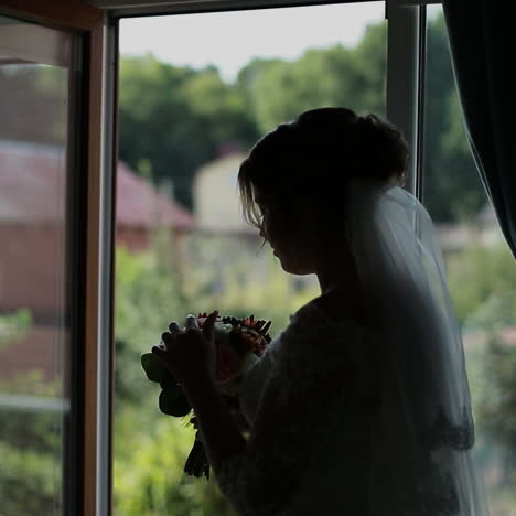 Beautiful bride stands by the window. Wedding bouquet Square video