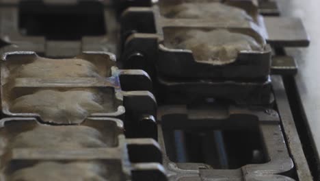 tight shot of momiji manju machine flipping molds on assembly line.