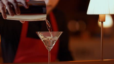 el camarero vertiendo martini del batidor.