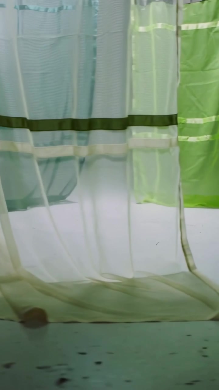 Vertical video: Starting dolly move, camera gliding low through sheer panels, showing pooling hems