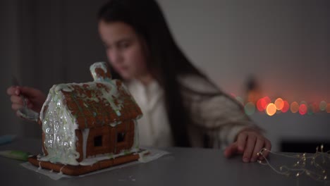 niña linda con pan de jengibre casa espeluznante con glaseado festivo y galleta en forma de fantasma. feliz halloween