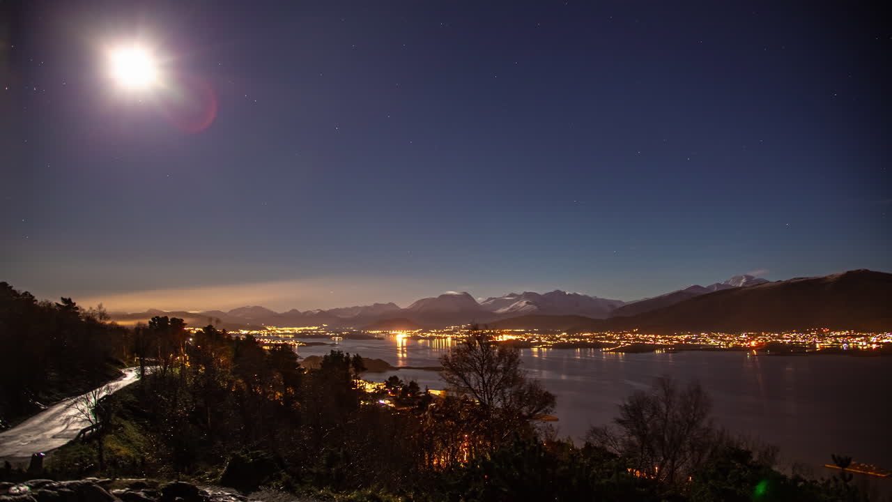 a lua e as estrelas cruzam o céu acima do porto marítimo de alesund, noruega - lapso de tempo noturno