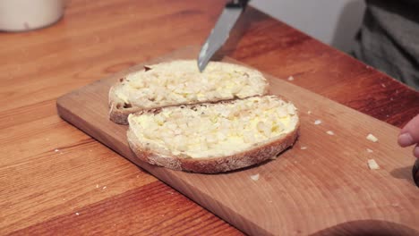Woman's hands puts garlic on two slices of bread smeared with butter