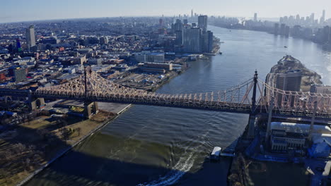 east river amidst buildings in city, drone flying backward from skyline
