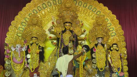 an indian man offering prayers to goddess durga during puja in kolkata.