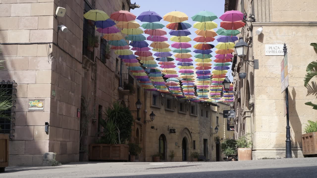 여름 햇살 아래 형형색색의 우산으로 뒤덮인 거리를 행복하게 달리는 귀여운 십대 소녀
