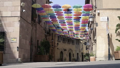 cute teen girl happily running down a street covered in colorful umbrellas in summer sunshine