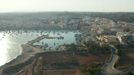 Strandstadt-Mit-Bucht-Voller-Boote-Auf-Der-Malta-insel-Bei-Sonnenuntergang,-Luftdrohnenperspektive