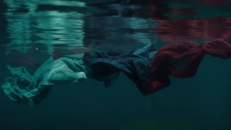 an ethereal dance of fabric underwater: beautiful, flowing textiles create mesmerizing patterns and colors beneath the surface amidst the reflection of light
