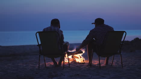 two friends are frying marshmallows around the fire they sit in the twilight by the river live chat