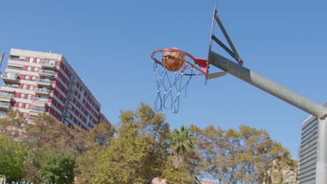 Allgemeine-Aufnahme-In-Zeitlupe-Eines-Jungen-Kaukasischen-Mannes,-Der-Auf-Einem-Straßenbasketballplatz-In-Barcelona,-Spanien,-Zu-Einem-Layup-Dribbelt-Und-Hineinfährt