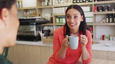 video of happy diverse woman and man drinking and talking at coffee shop