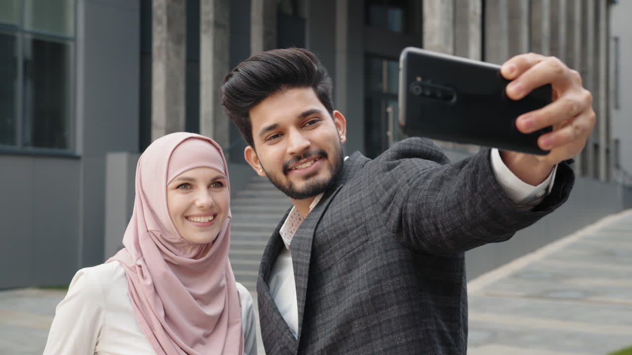 una pareja tomando una selfie fuera de un edificio moderno