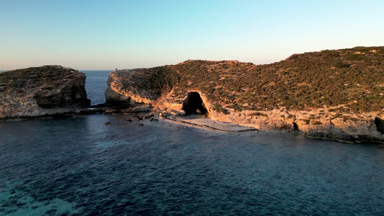 Drone Flying Away from a Sea Cave on Comino Island at the Blue Lagoon in Malta at Sunrise.