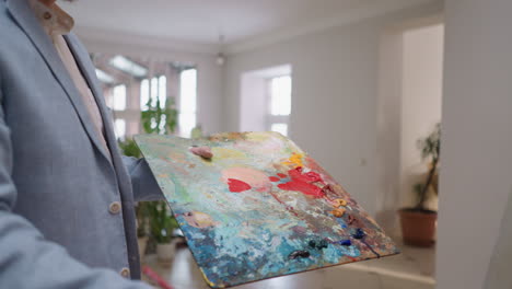 artist mixing paints on a palette in his studio