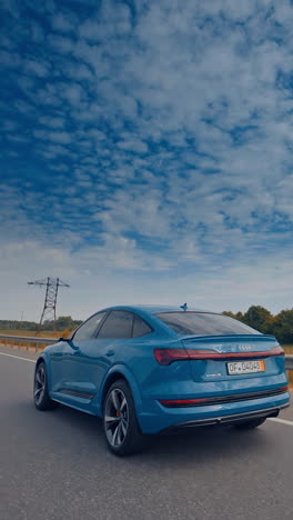 modern electric car on the road with blue sky. luxury comfortable ecology electric vehicle on the road. vertical video