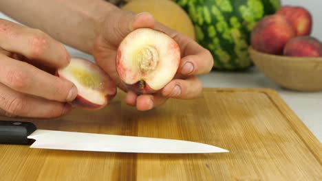 Gut-Gearbeitete-Hände-Bereiten-Einen-Pfirsich-Zum-Schneiden-Vor