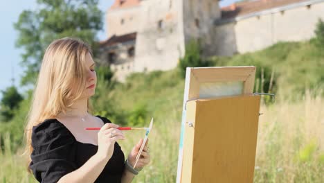 woman painting outdoors with a castle in the background