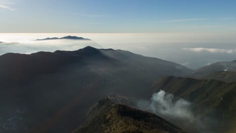 montañas nebulosas al amanecer en génova, liguria, con nubes anidadas entre los picos, vista aérea