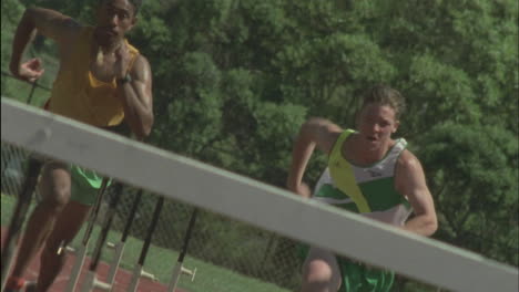 male runners commence a hurdle race